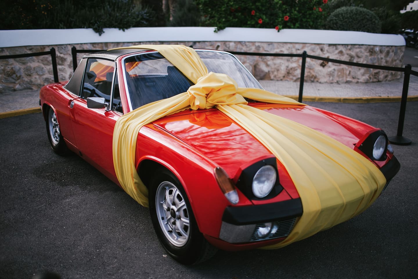 A red vintage Porsche wrapped in a yellow gift bow