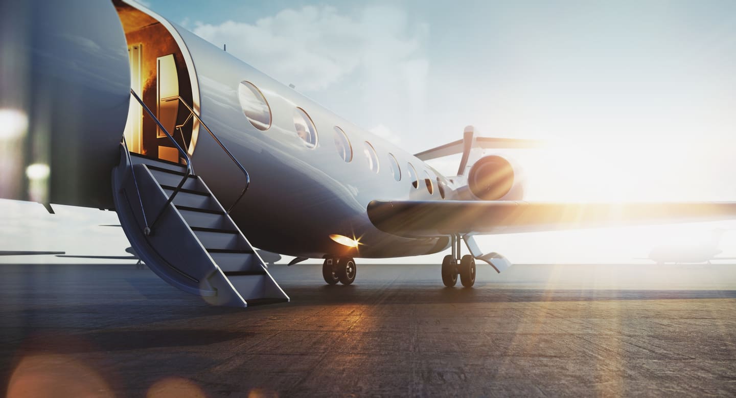 A private jet with its stairs down on the runway at sunset, cabin lights glowing