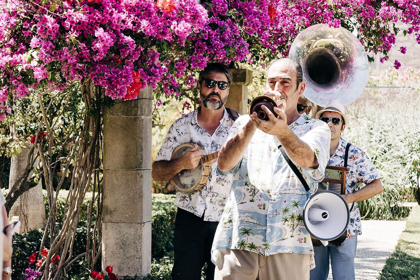 A brass band in Hawaiian shirts playing beneath pink bougainvillea