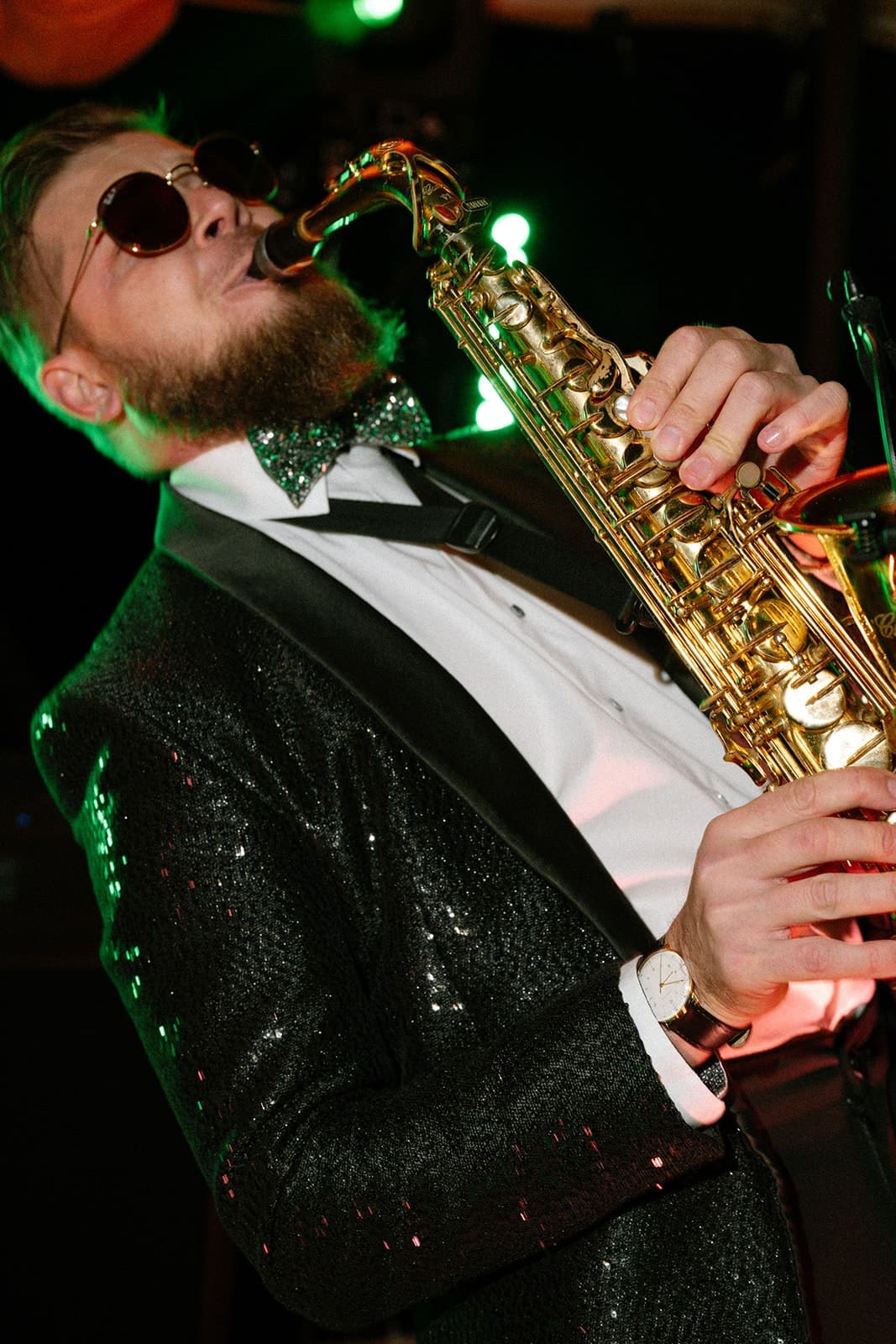 A saxophonist in a black sequined jacket playing at a private party